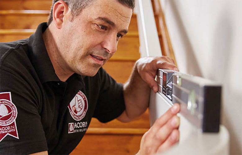 Stairlift technician measuring the stairs for proper stair lift installation